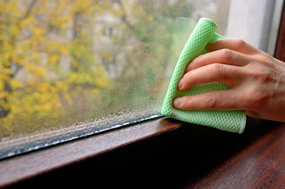 Window condensation, hand wiping away moisture