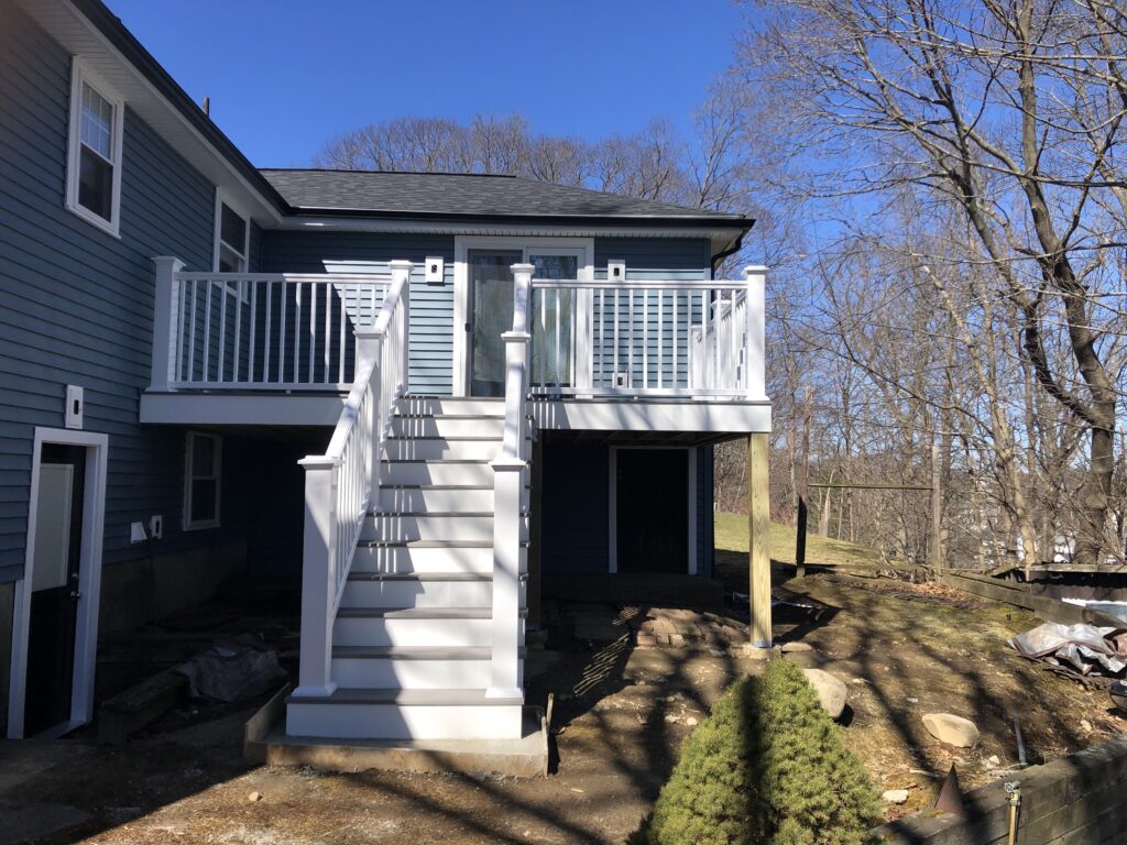 Newly built deck with white railings in the back of a blue house